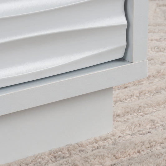 Close-up of the textured drawer front on the white coffee table, showcasing the coastal wave design and smooth white finish.