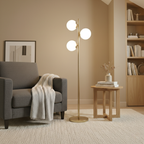 Modern gold floor lamp with three spherical opal glass shades, standing on a round metal base in a cozy living room.