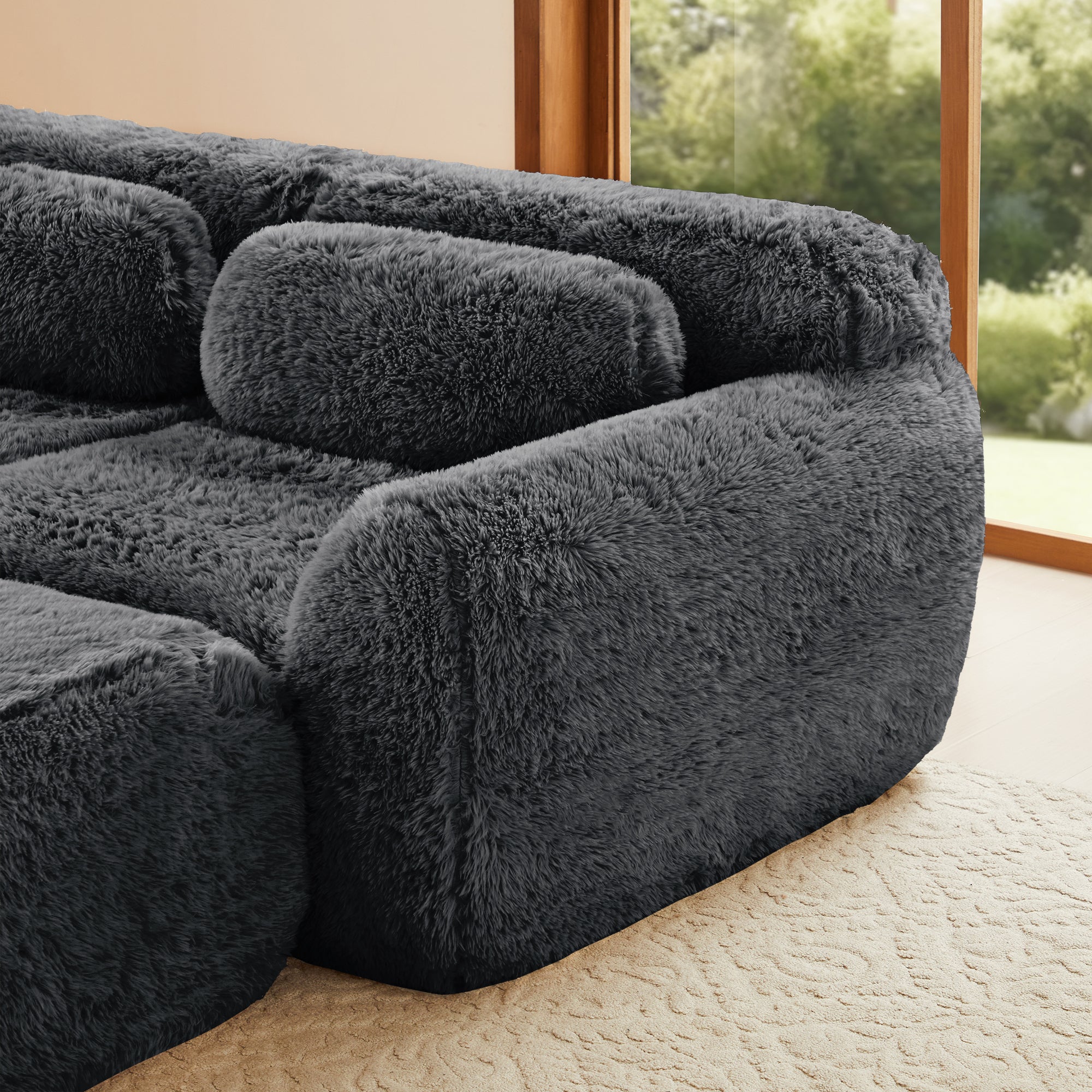 Armrest and cushion detail of dark grey modular sectional sofa. Plush fabric and rounded edges offer a modern, inviting look.