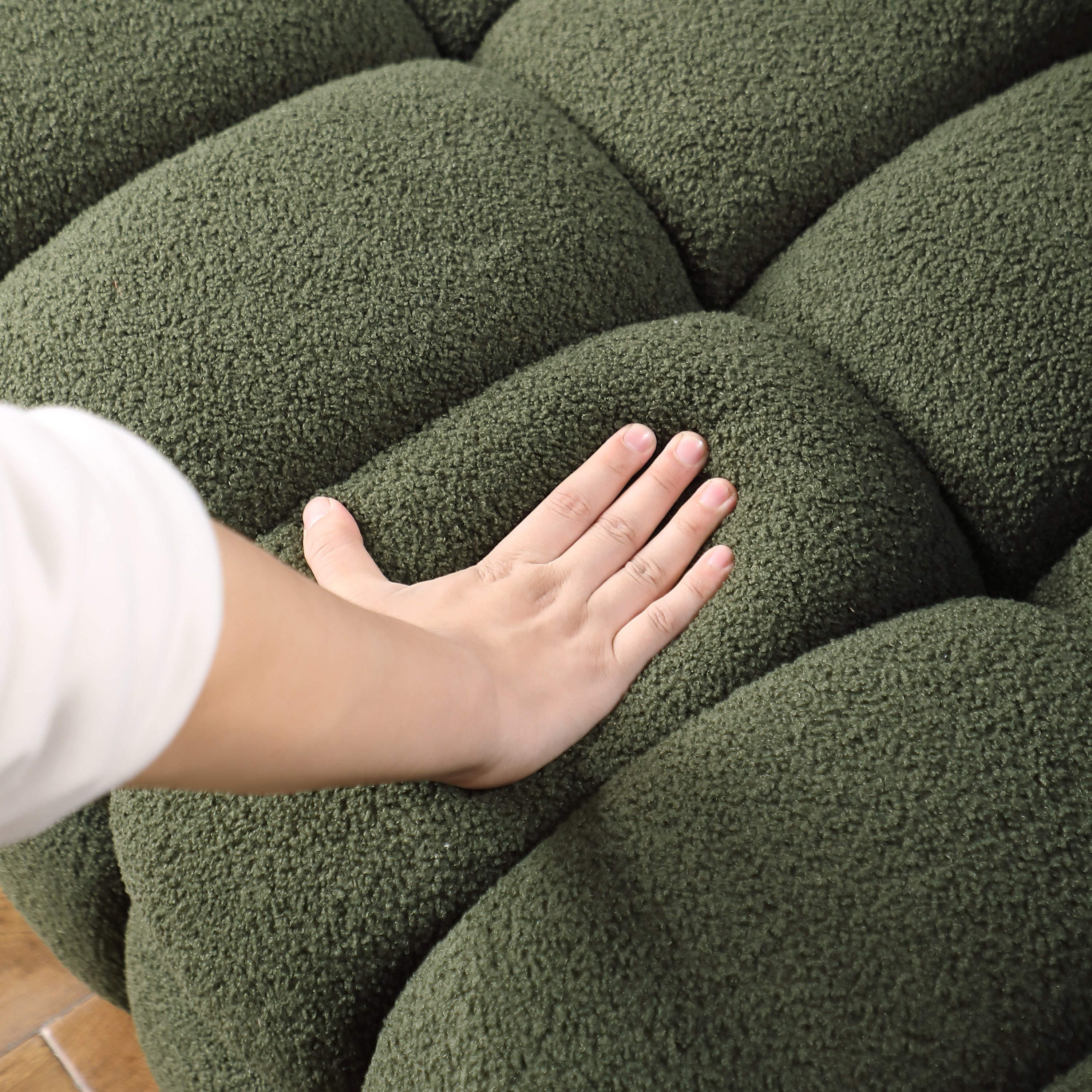 Hand pressing into the cushion of Olive Green Boucle Sofa - 3 Seater, Marshmallow Cozy, highlighting its softness and comfort.