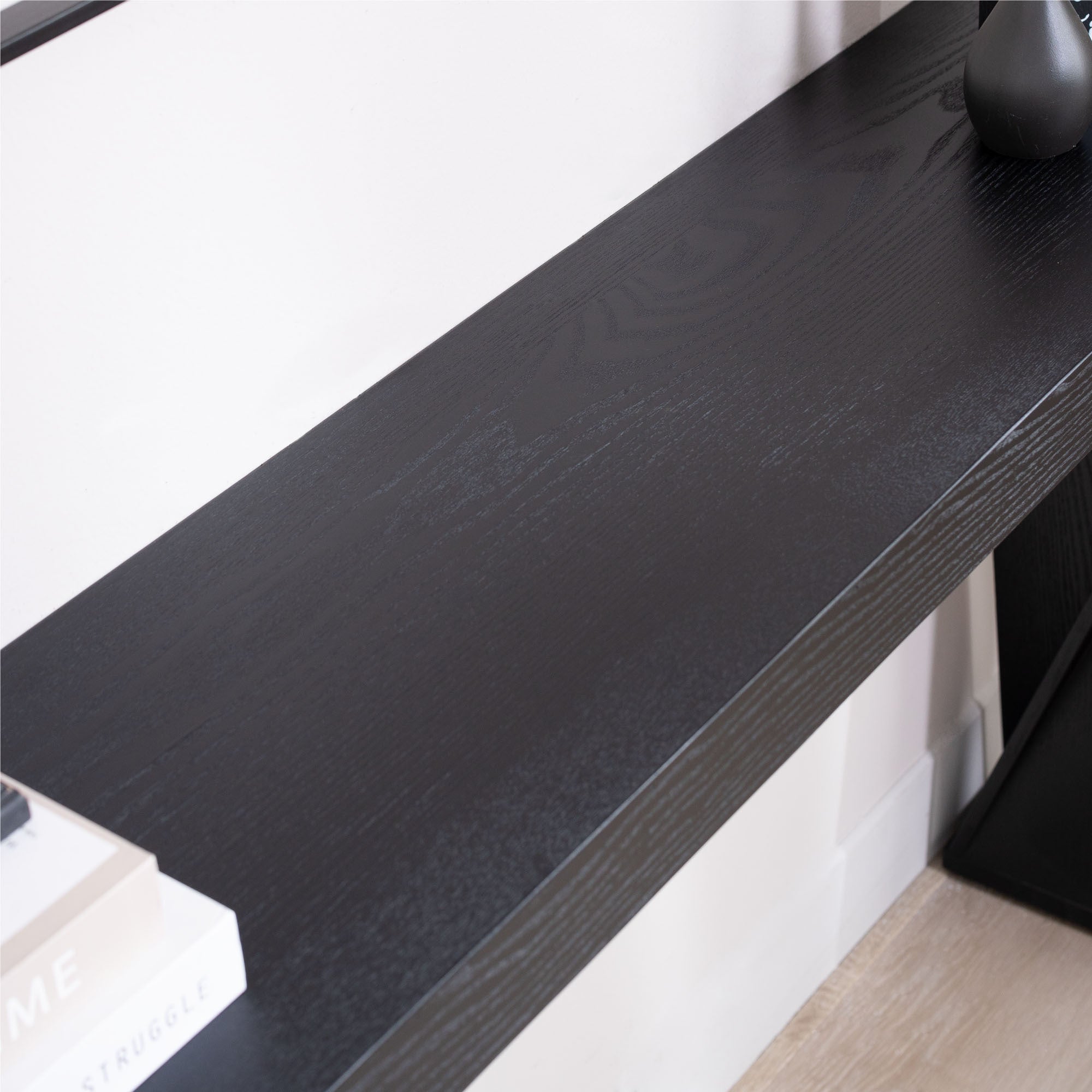 Top view of modern black console table showing the smooth, narrow surface with visible wood grain texture.