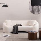Minimalist white curved sofa styled in a modern living room with neutral tones and accent furniture.