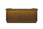 Counter-height wooden bar in a latte finish featuring a vertical slat design, flat countertop, and warm, lit front panel.