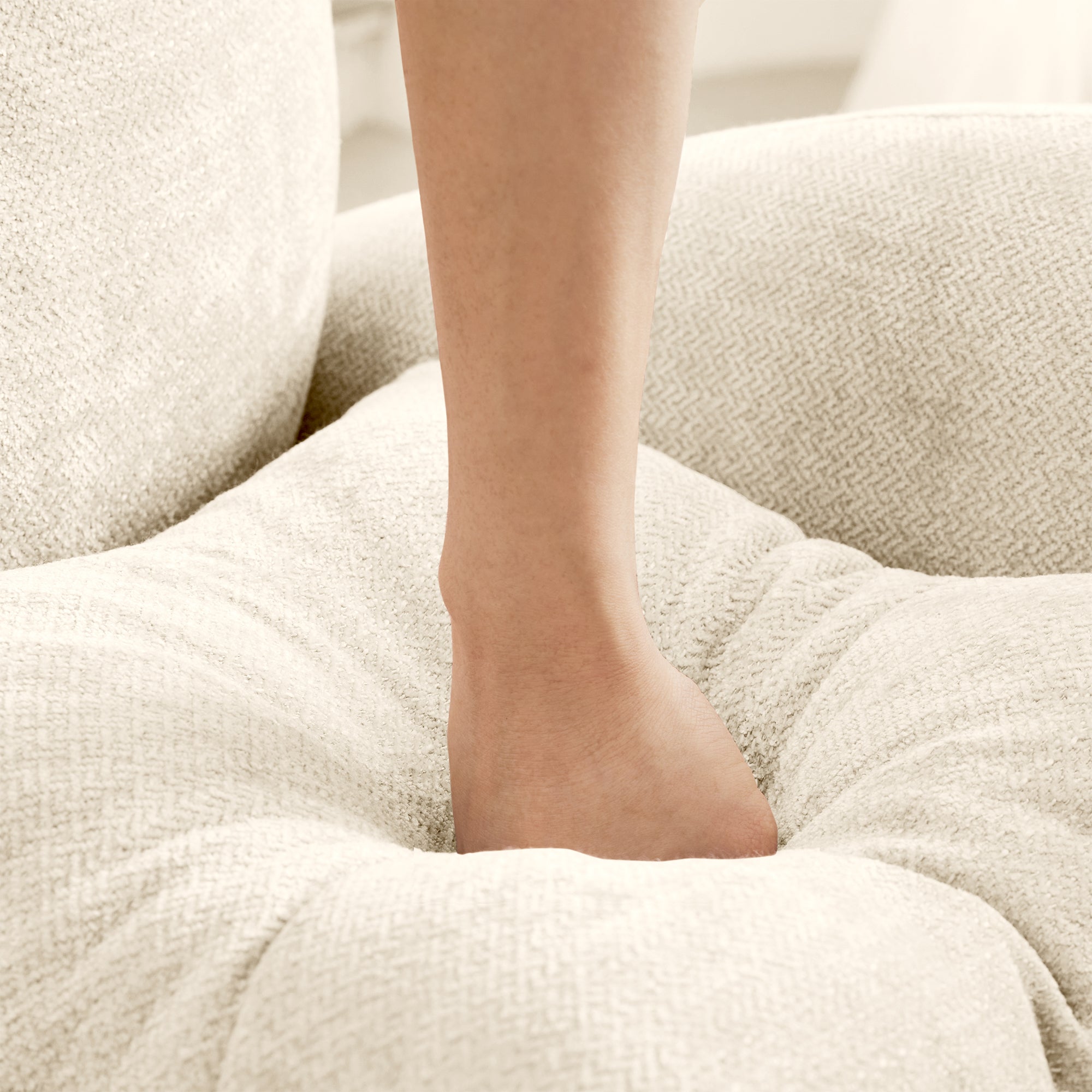 Foot sinking into the plush chenille cushion of the Modular L-Shaped Sofa - Sectional Couch, demonstrating its supportive softness.