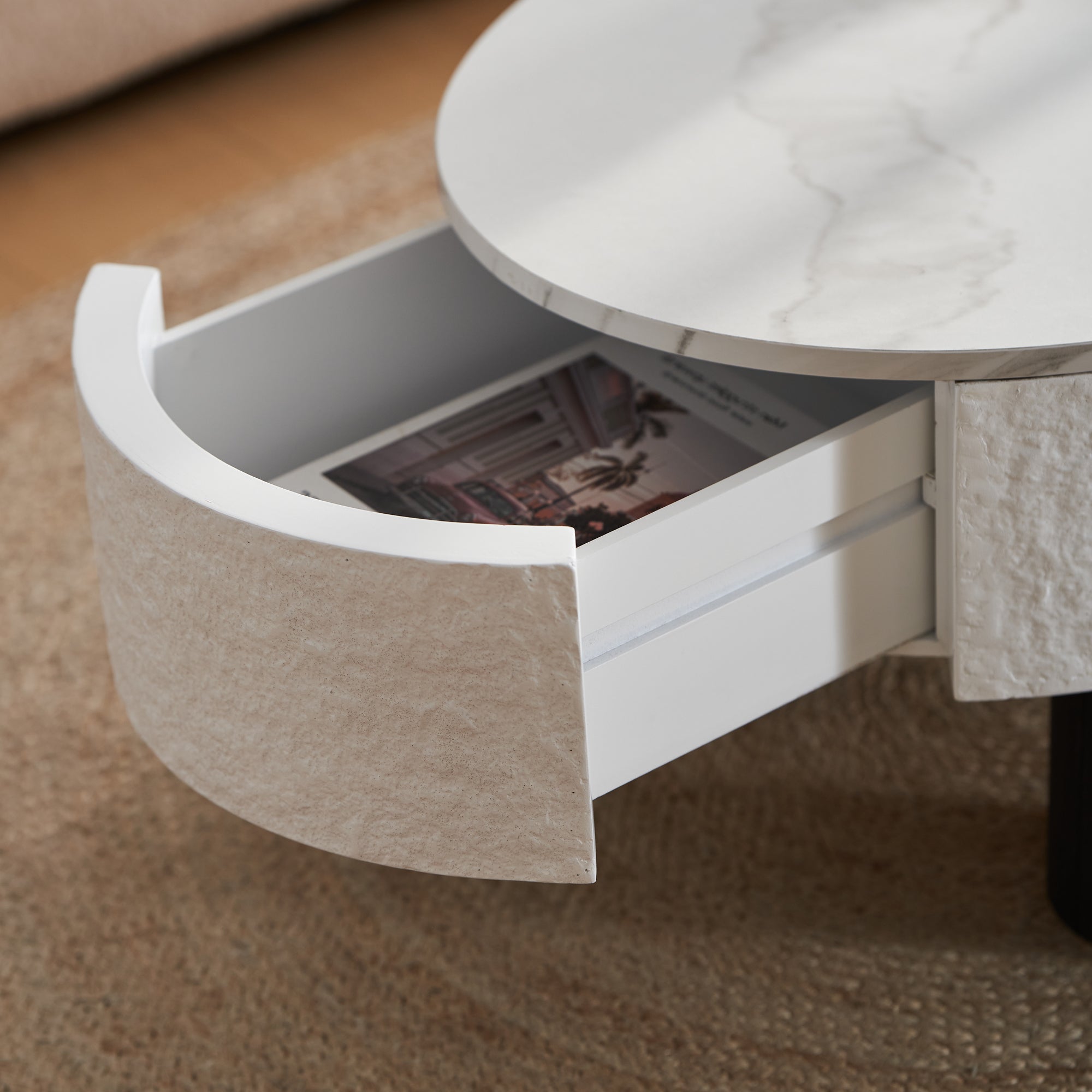 Detail of the side drawer in the oval coffee table with storage, revealing interior space for magazines and accessories.