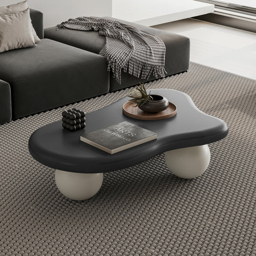 Modern Cloud Shaped Coffee Table with black top and white ball legs in a gray-toned living room. Stylish centerpiece for contemporary furniture setups.