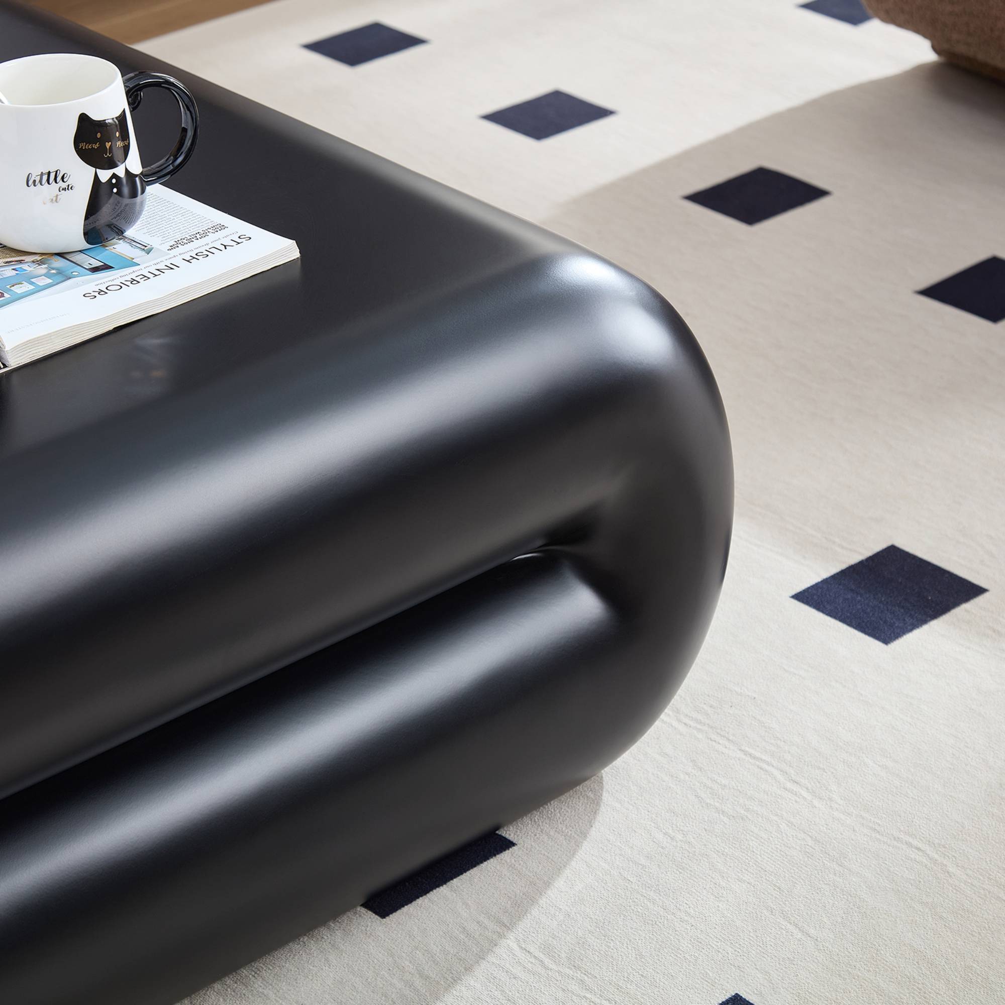Close-up of black fiberglass coffee table corner showing glossy finish and curved edge, emphasizing its modern craftsmanship.
