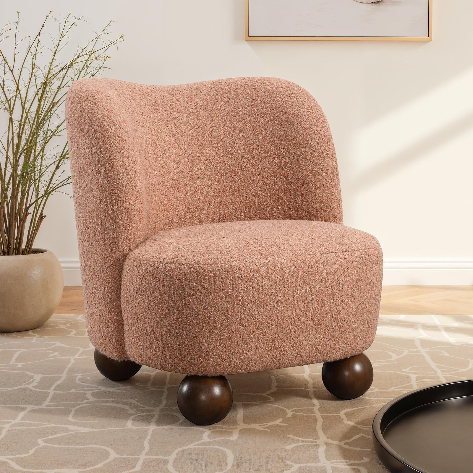 Modern pink accent chair in boucle upholstery, featuring a curved back and round wooden legs, placed in a cozy living room setting.