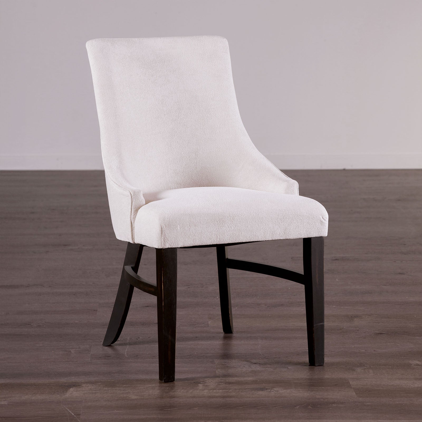 Transitional arm chair with padded wingback in beige fabric and black wood legs, ideal for modern dining room settings.