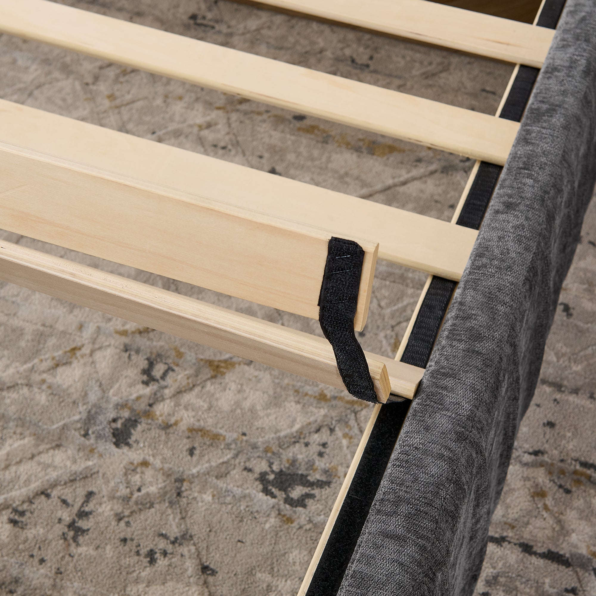 Wooden slat support system of queen upholstered bed. Solid frame construction ensures durability with built-in table and lamp features.