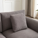 Detail of square throw pillow on gray modular sofa, emphasizing the soft fabric and cohesive design of the upholstered furniture.