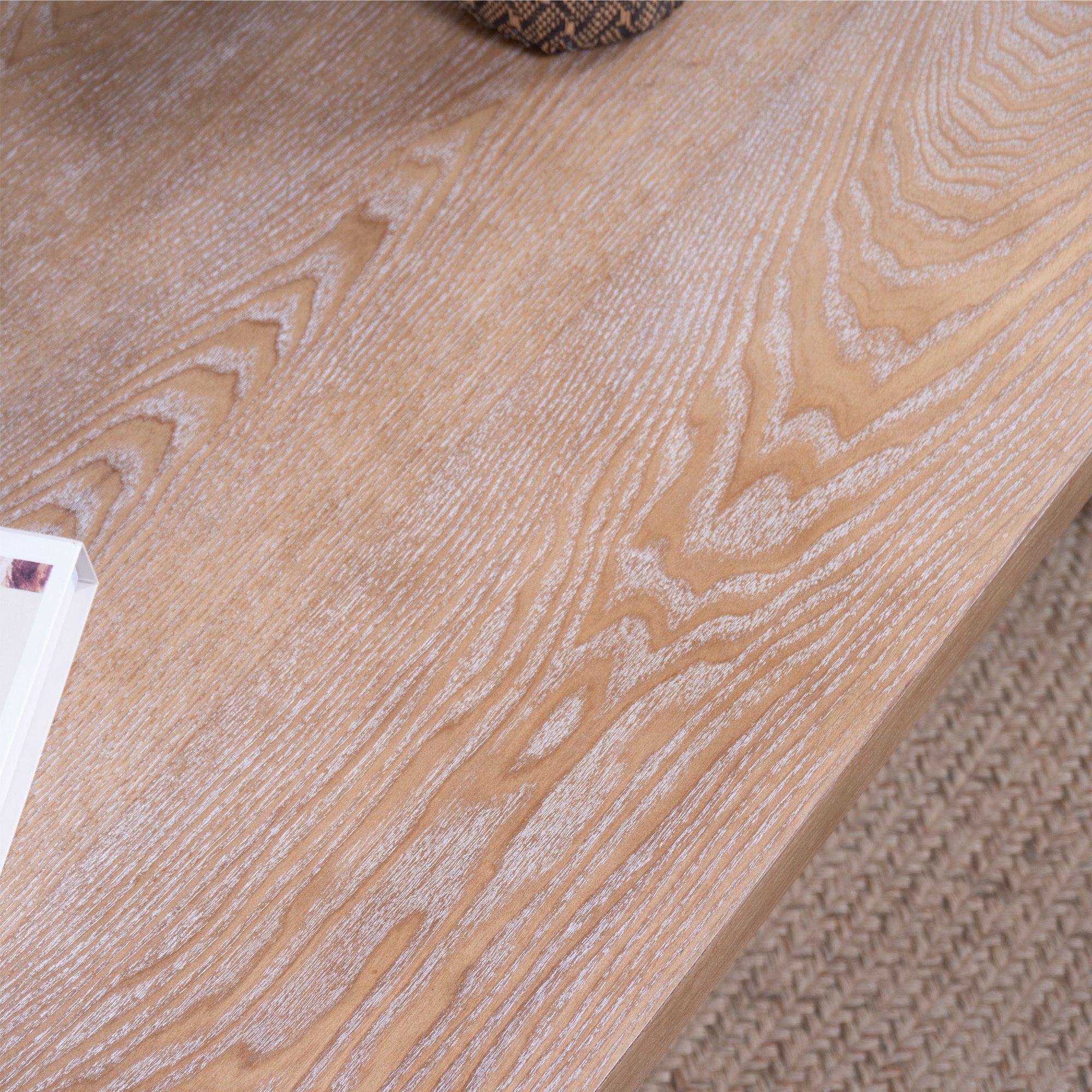 Close-up of tabletop surface on rustic carved wood coffee table, featuring natural wood grain and hand-painted finish.