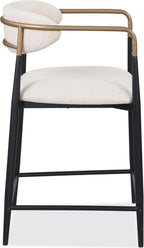 Side profile of a counter height chair with sleek black metal legs, gold armrest frame, and curved cushioned backrest in beige fabric.