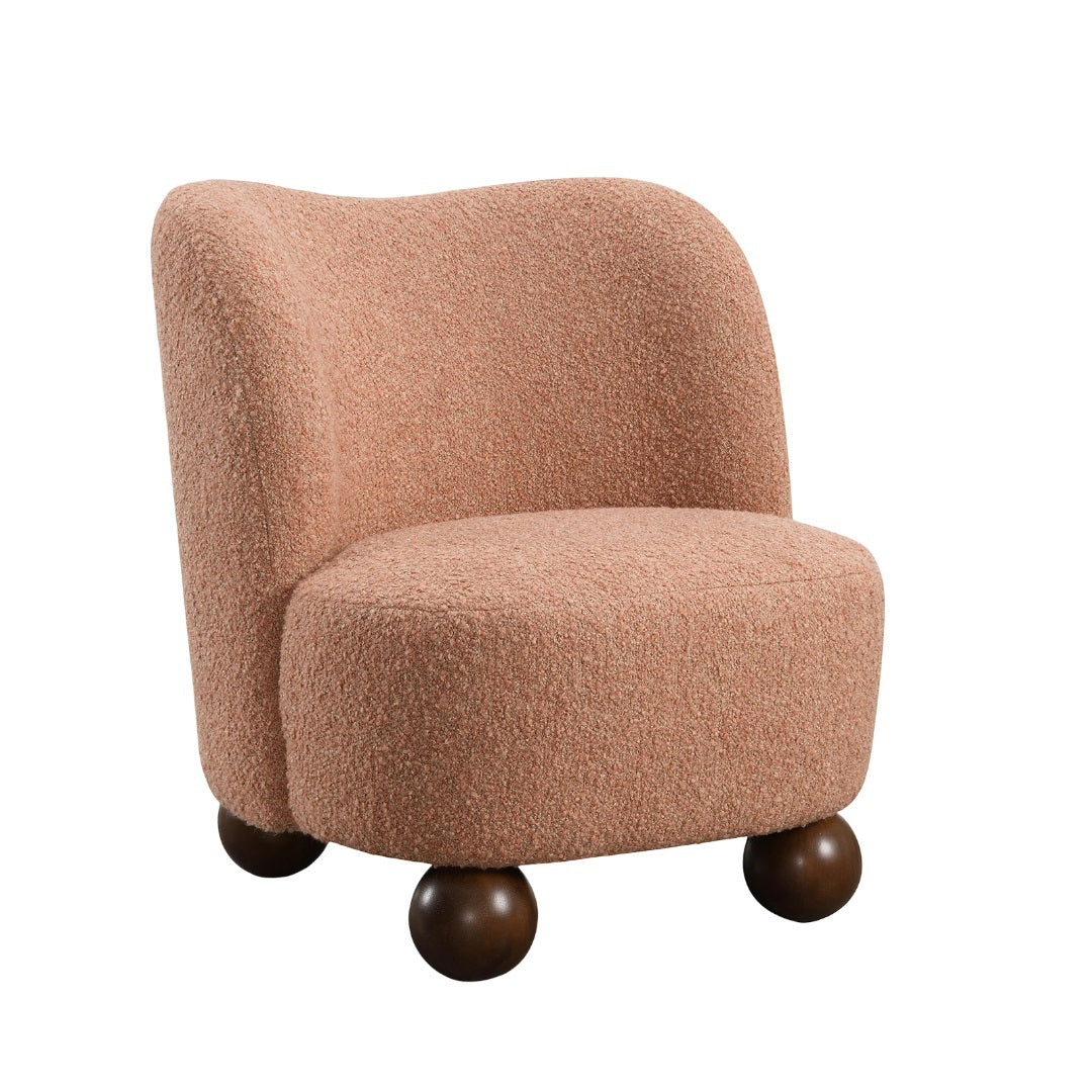 Standalone view of pink accent chair with curved back and boucle texture, supported by dark wooden ball feet for a modern look.