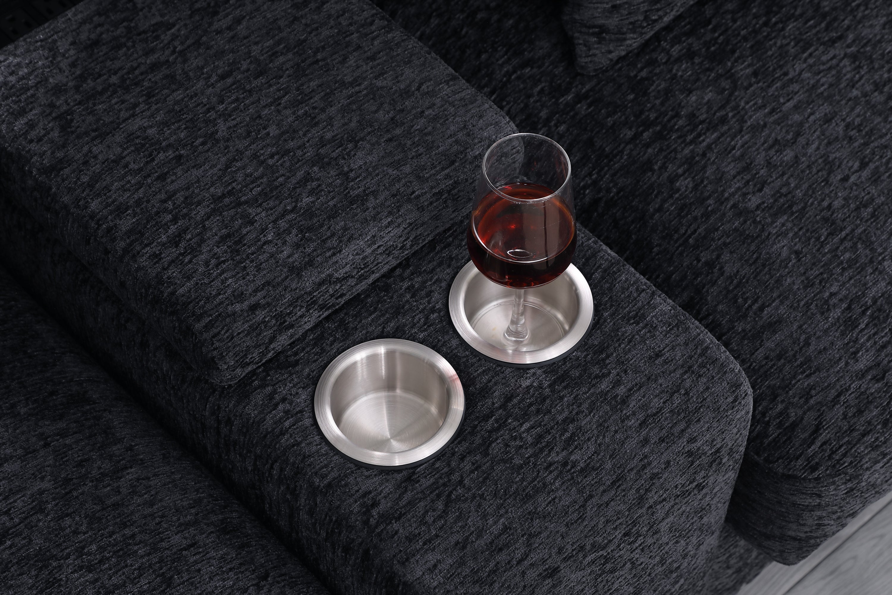 Close-up of stainless steel cupholders on Celine sectional sofa armrest. Dark gray fabric with modern living room features.
