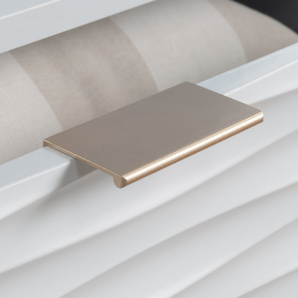 Gold-tone drawer pull on the white coffee table adds a touch of elegance to the coastal-inspired furniture piece.