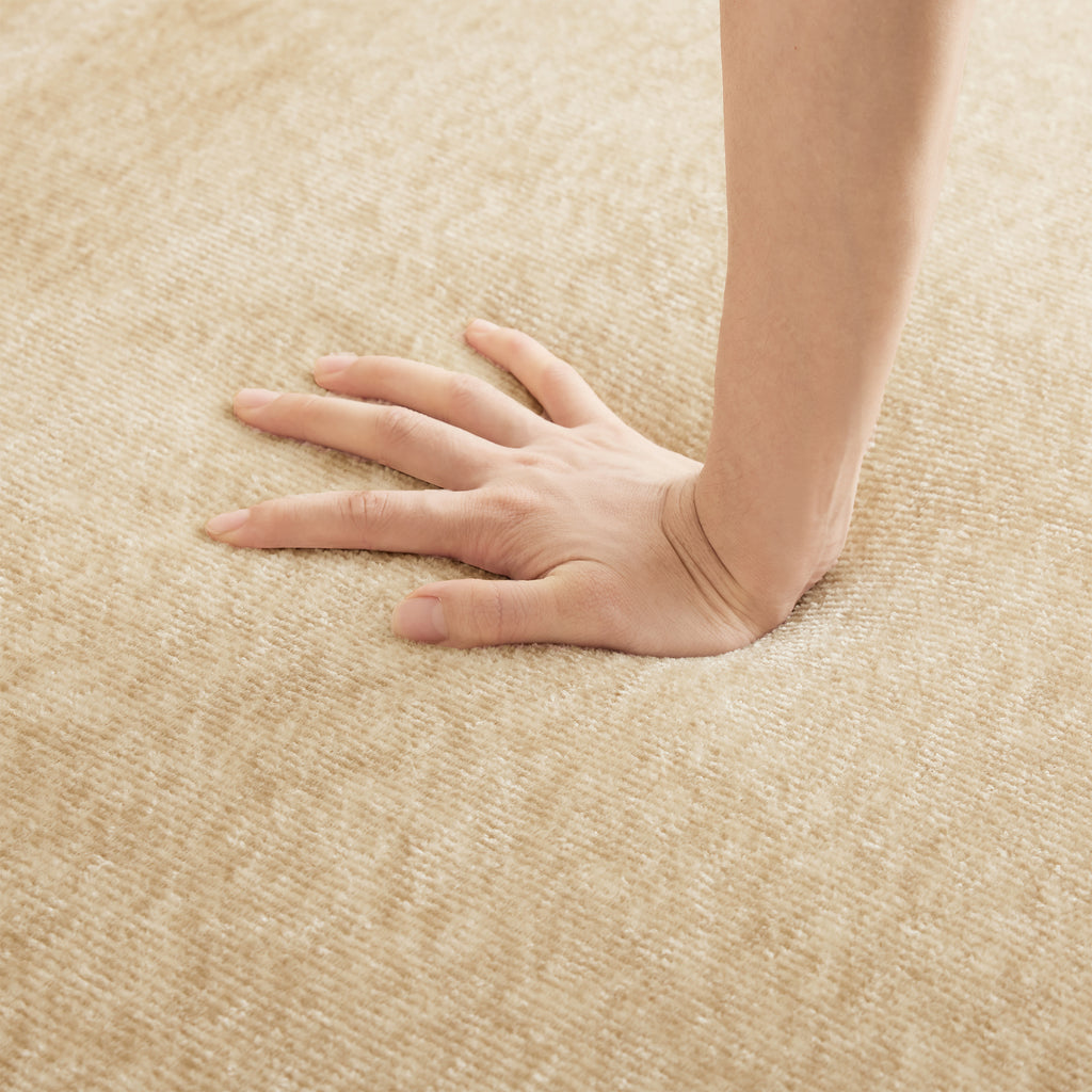 Hand pressing into seat cushion of Modular Velvet Sectional Sofa, demonstrating plush, supportive comfort in light camel velvet.