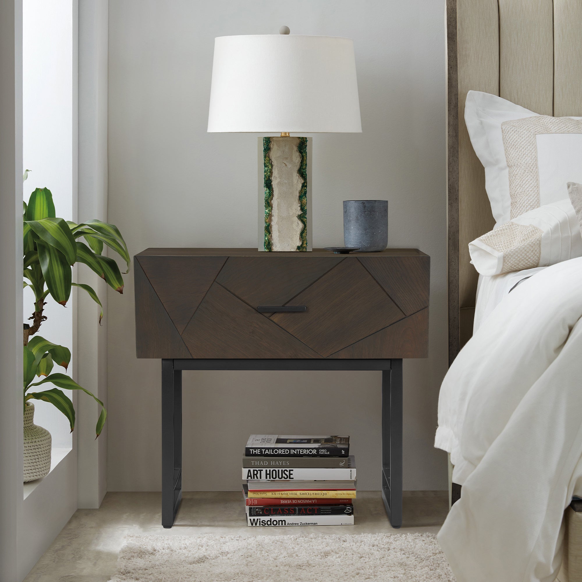 Modern dark oak wood nightstand featuring a geometric drawer front and black metal legs, styled in a bedroom setting.