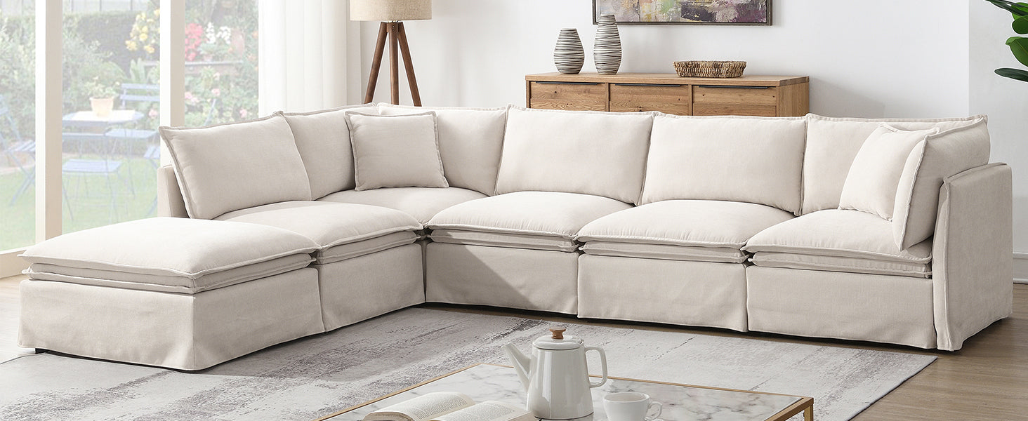 Spacious modular sectional sofa with ottoman in beige, arranged in a contemporary living room with wood accents and soft lighting.