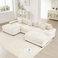 Oversized cream corduroy modular sectional sofa with deep seats, wide armrests, and a matching ottoman.