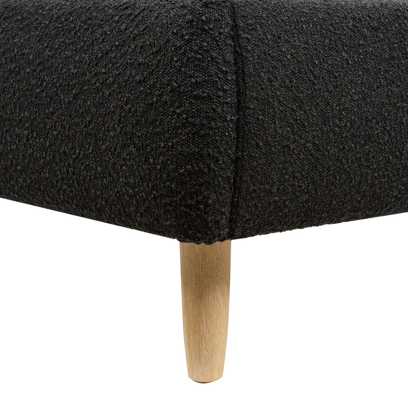 Close-up of Curved Upholstered Platform Bed Queen, Ebony Black Boucle showing textured fabric and tapered wooden leg detail.