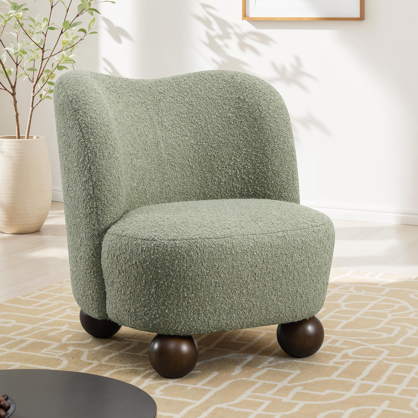 Green boucle accent chair with rounded back and dark wood ball feet. Ideal for contemporary spaces needing sturdy and stylish seating.