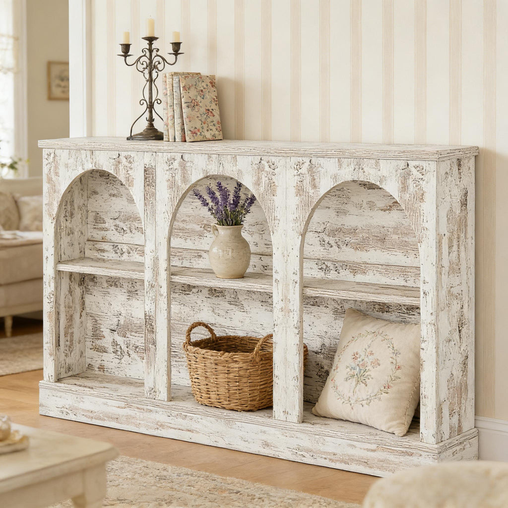 Distressed white wooden console table with three arched storage compartments, shelves, and farmhouse decor.