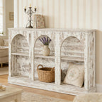 Distressed white wooden console table with three arched storage compartments, shelves, and farmhouse decor.