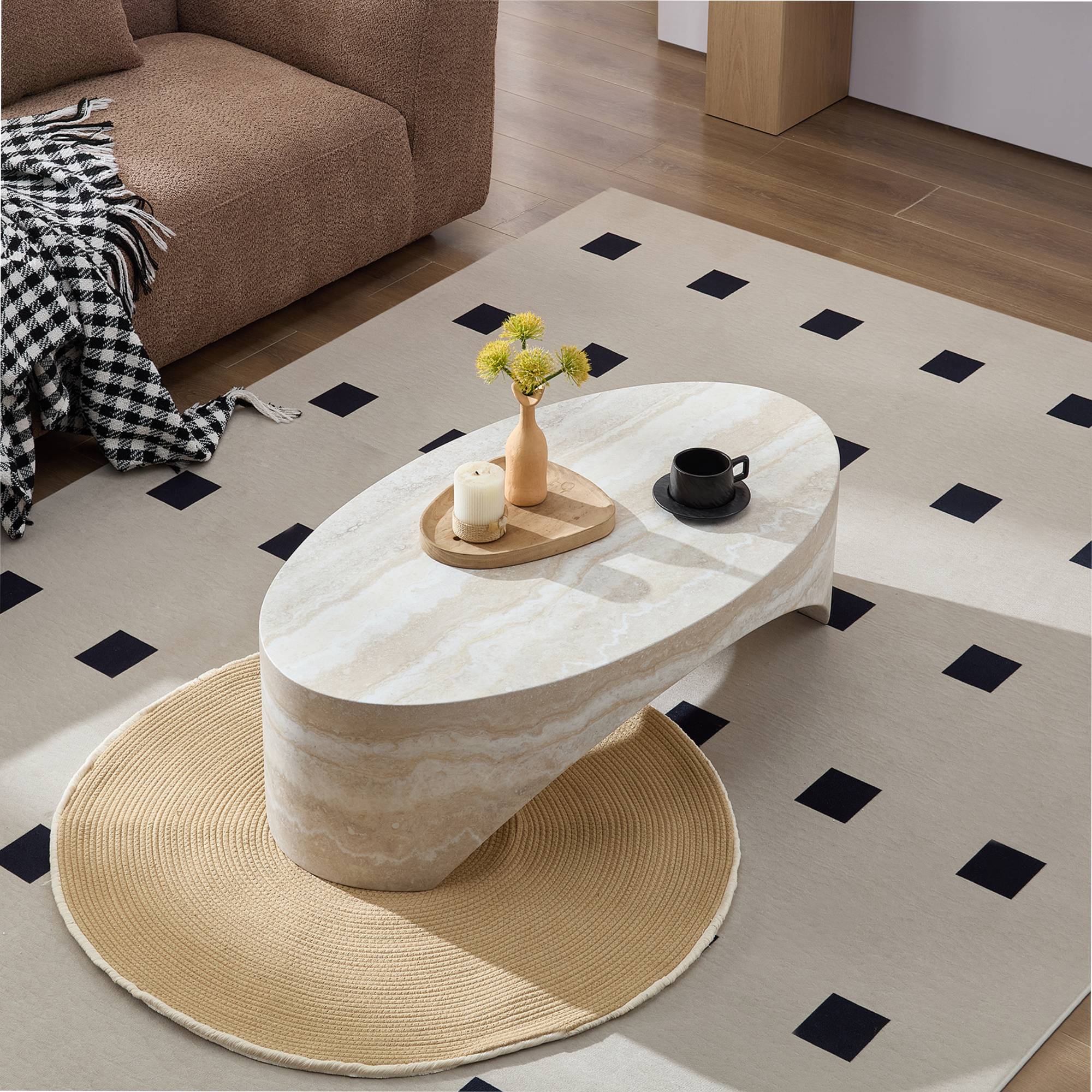 Top view of oval marble coffee table with smooth surface and curved design, placed on a beige rug with black square accents.