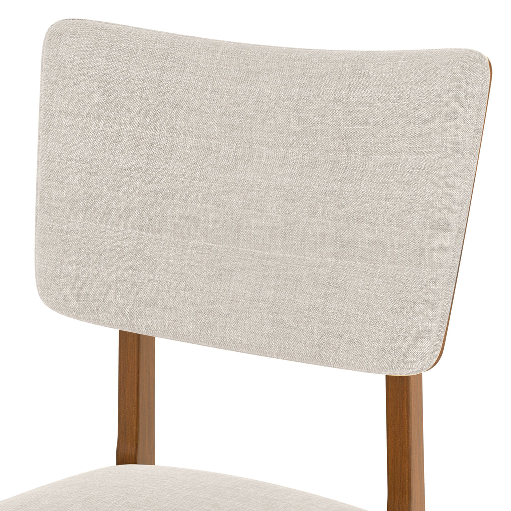 Close-up of upholstered chair backrest from farmhouse dining table set for 4, featuring beige fabric and wooden frame.