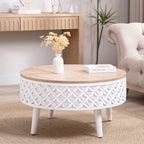 Boho modern round coffee table with carved white base and wood top, styled with vase and book in a bright living room.