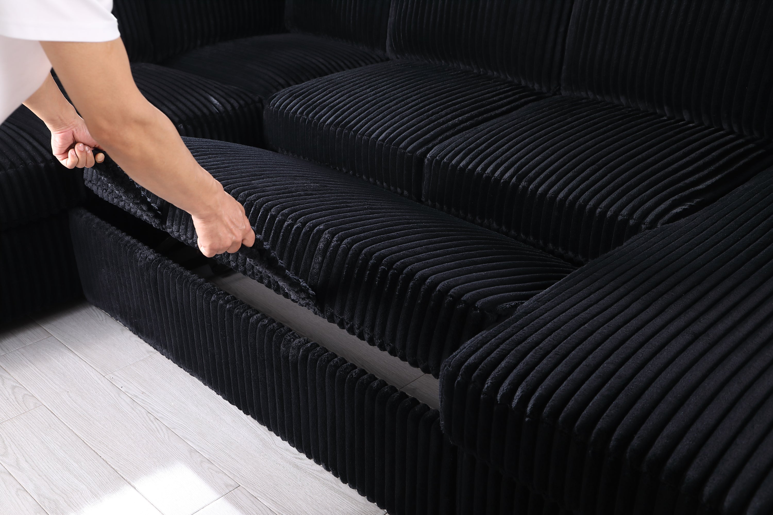 Close-up of hidden storage compartment under seat cushion of convertible sleeper sofa, showcasing practical design and easy access.