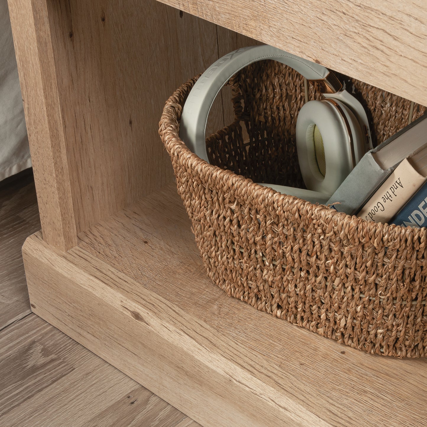 Close-up of the night stand's lower shelf holding a woven basket with headphones and books, showcasing storage functionality and rustic brown finish.