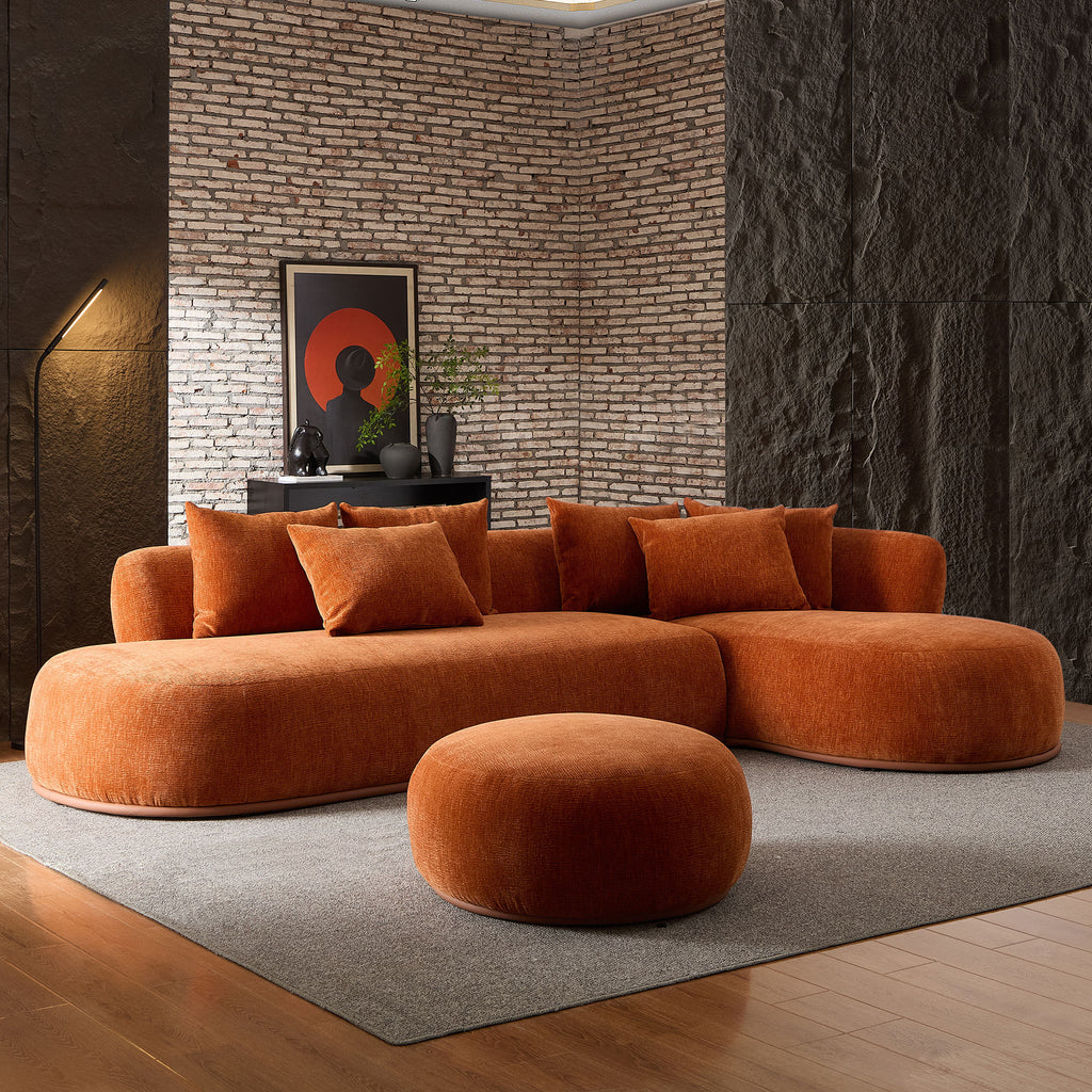Modern orange oversized L-shape sectional sofa with ottoman in a dark-toned room, offering bold style and spacious seating.