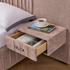 Detail of built-in nightstand drawer on upholstered queen bed, showing storage space with books and coffee cup on top.