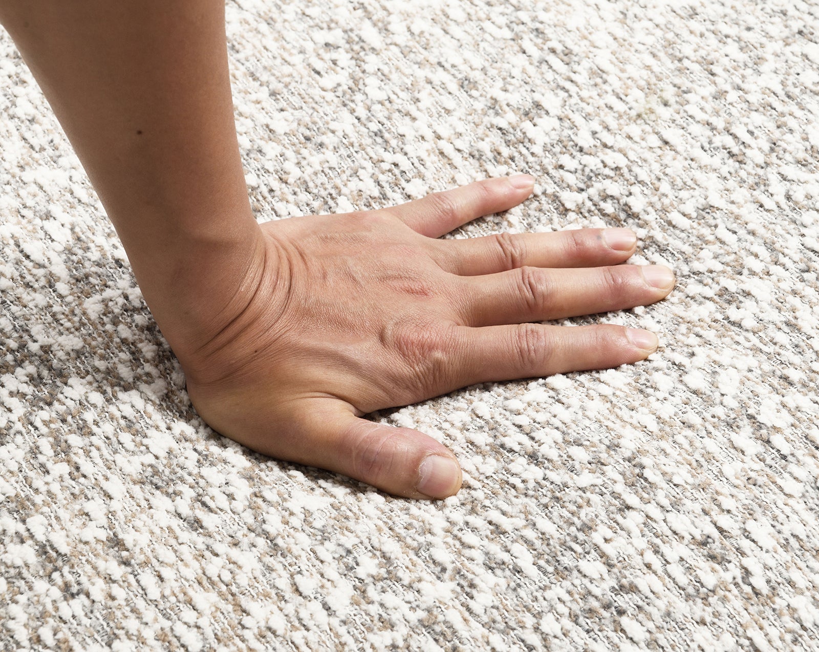 Hand pressing into the brown boucle upholstery of the swivel chair, demonstrating the high-density foam's softness and support.