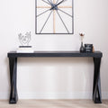Modern black console table with crossed legs styled in a hallway, featuring decorative accents and minimalist decor.
