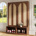 Walnut farmhouse hall tree with arched rattan-panel doors and an open lower shoe storage shelf in a sunlit entryway.