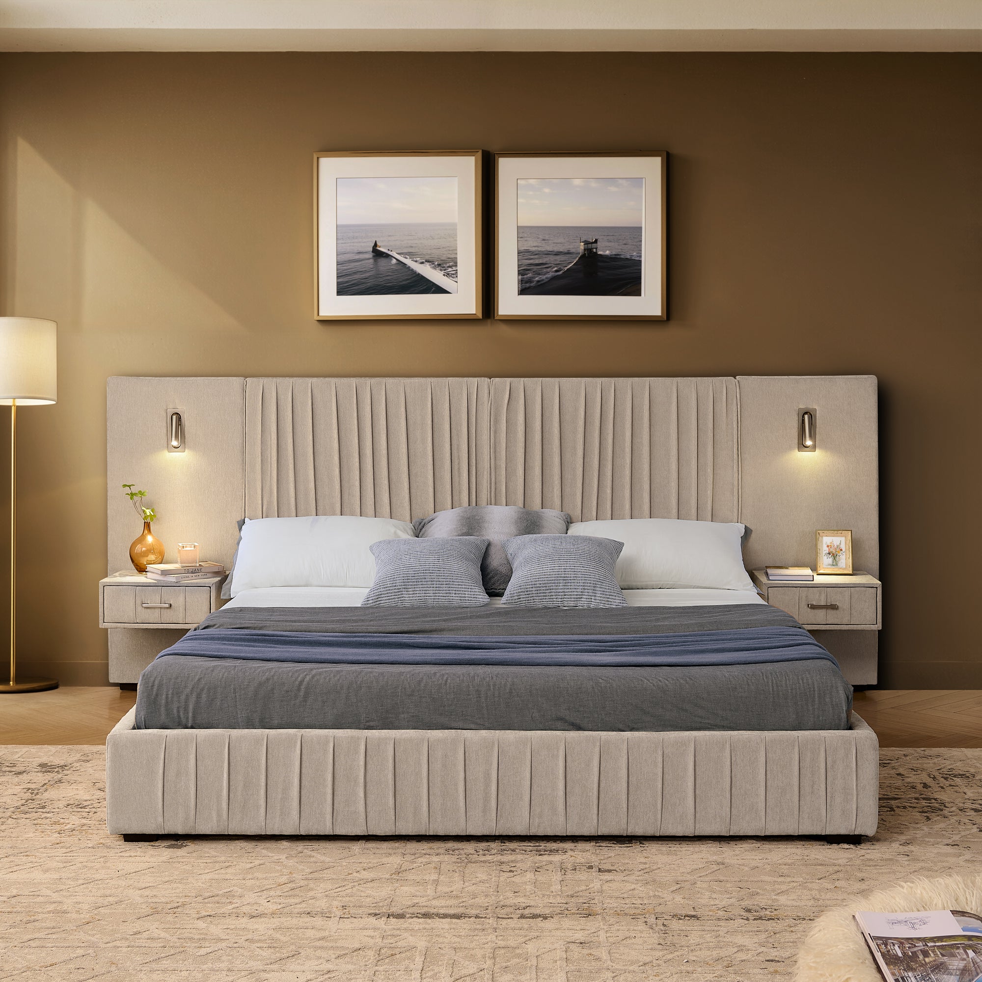 Front view of queen upholstered bed frame with pleated headboard, dual nightstands, and mounted reading lights in a warm-toned bedroom.