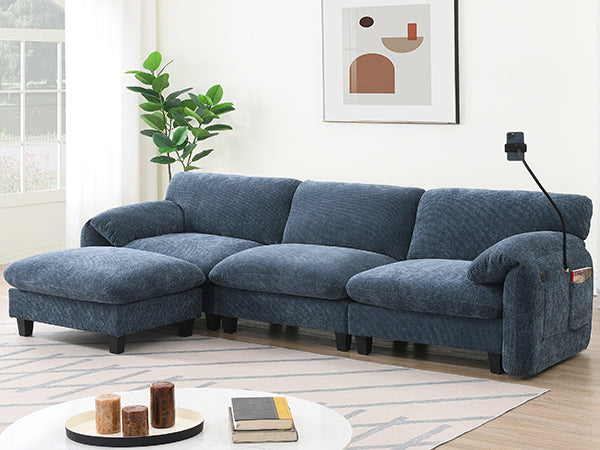 Living room setup featuring modular sectional sofa with USB charger and ottoman. Blue fabric upholstery complements minimalist decor.