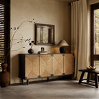 Black wood sideboard with four woven seagrass doors featuring a geometric pattern, set against a warm neutral wall.