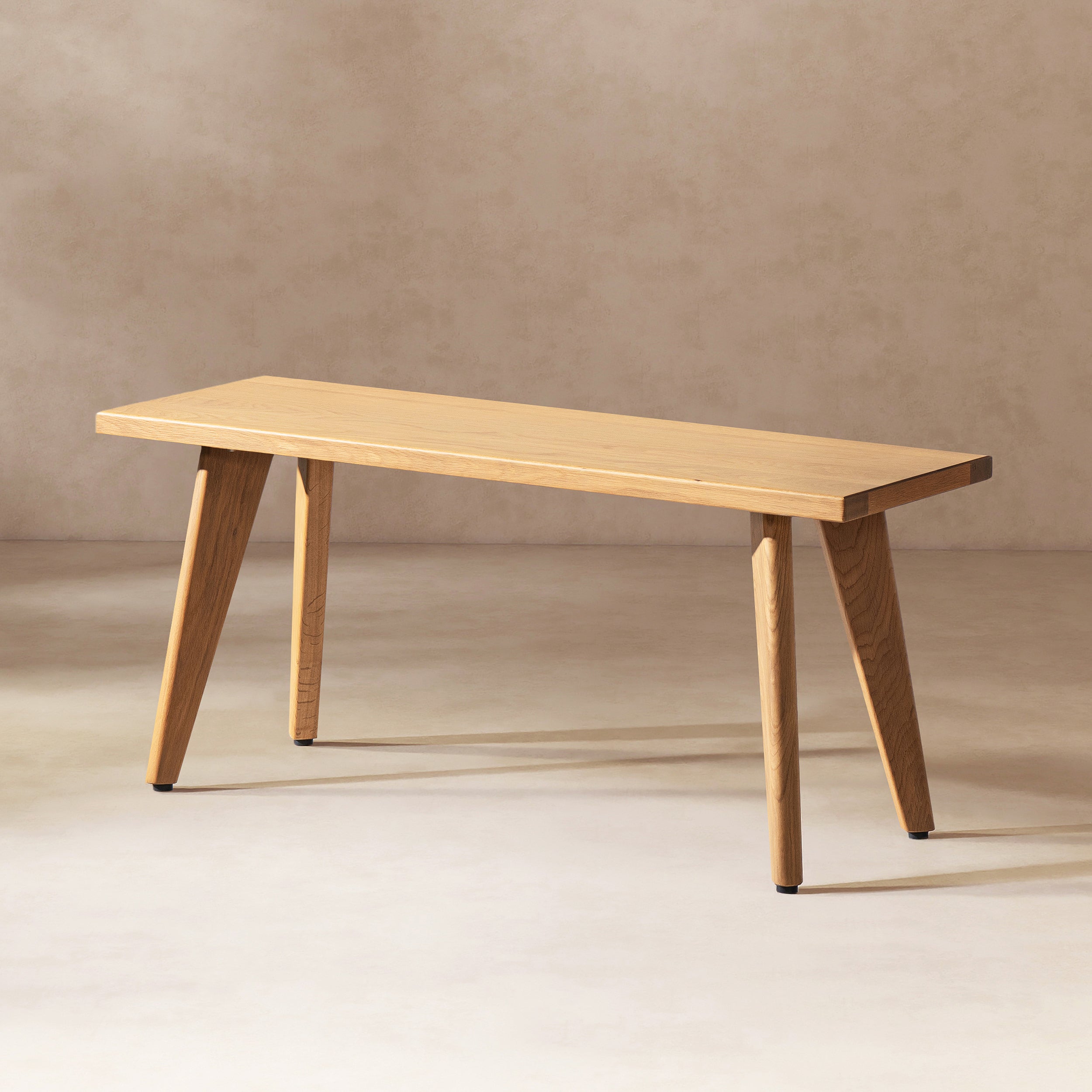 Capri 41.5' solid red oak wood bench with angled legs shown in a neutral studio setting, highlighting its slim and modern profile.