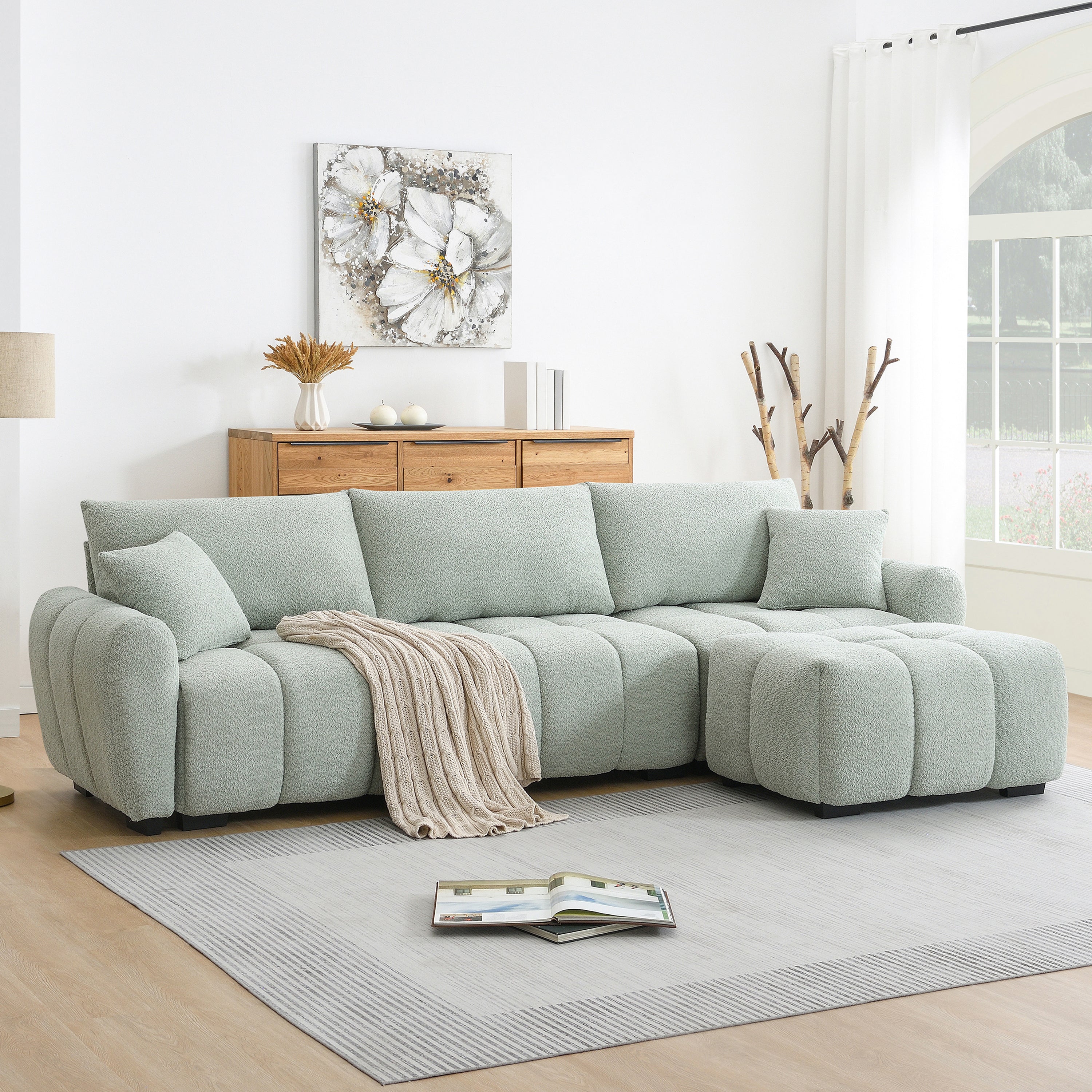 Modular sectional sofa with ottoman in boucle fabric, styled in a modern living room with wood accents and neutral tones.