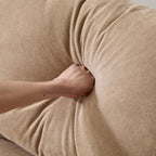 Hand pressing into the back cushion of the 99 in. modular velvet sectional sofa, showing plush support and high-quality fill.