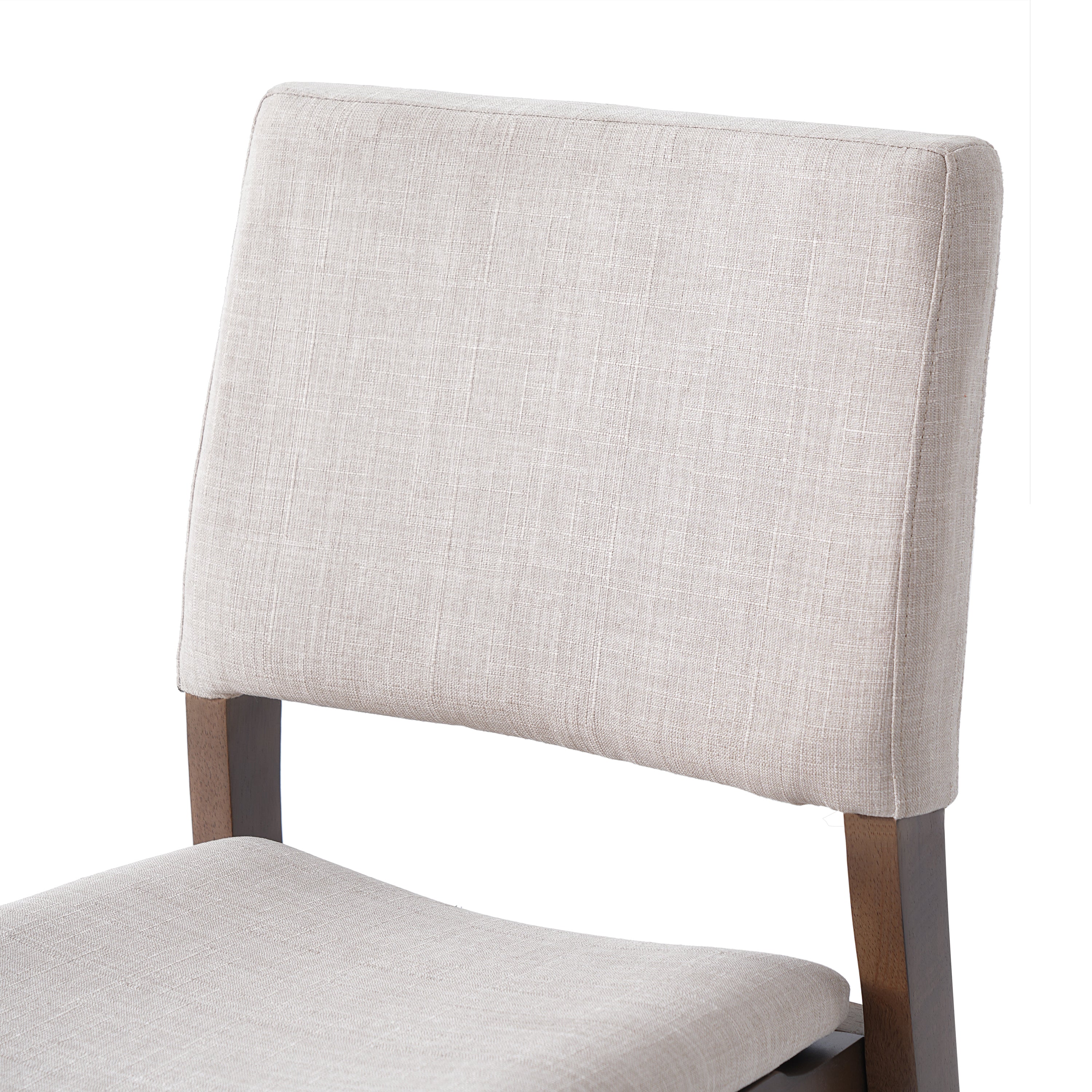 Close-up of the cushioned backrest in beige fabric on a walnut finish dining chair from the Modern Dining Set collection.
