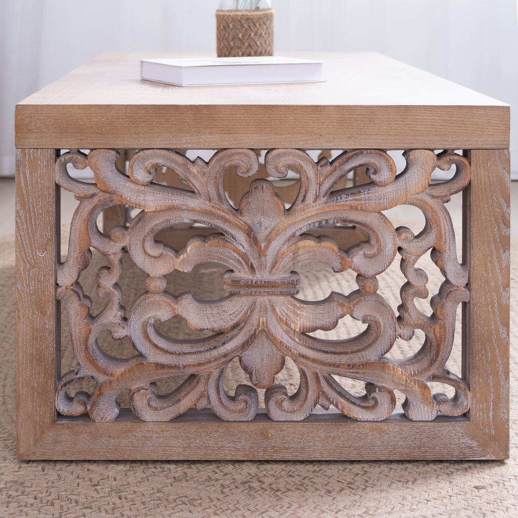 Detailed close-up of ornate carved side panel on rustic wood coffee table, showcasing intricate handcrafted floral patterns.