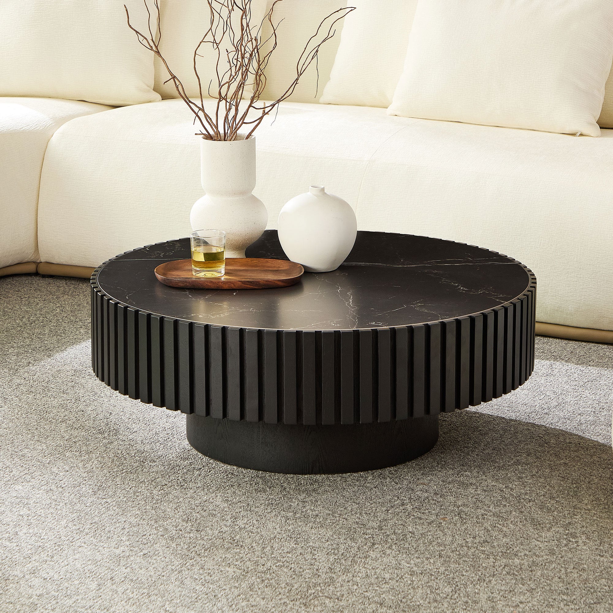 Modern round coffee table with 35.43'' black sintered stone top and fluted base, styled in a cozy living room with neutral decor.