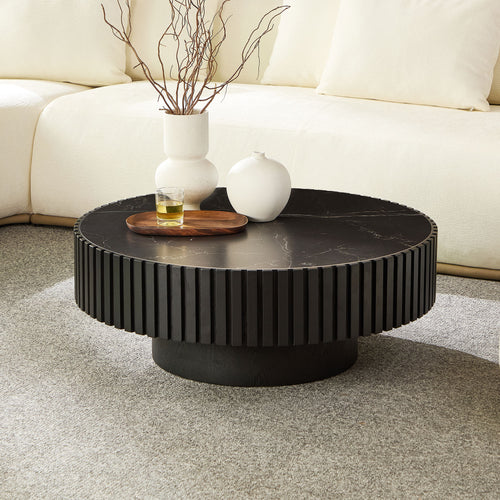 Modern round coffee table with 35.43'' black sintered stone top and fluted base, styled in a cozy living room with neutral decor.