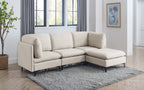 Beige linen modular sectional sofa with plush cushions and sleek black metal legs on a grey area rug in a bright room.