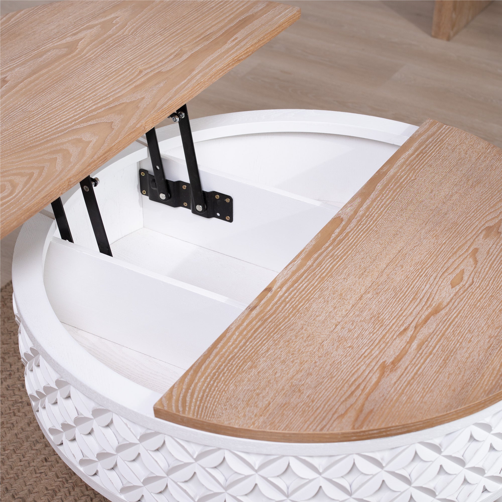 Close-up of lift-top storage compartment in round coffee table with white carved base and wood top.